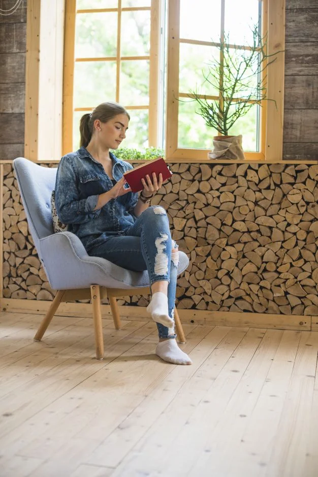 Persona leyendo un libro en sillón con luz natural